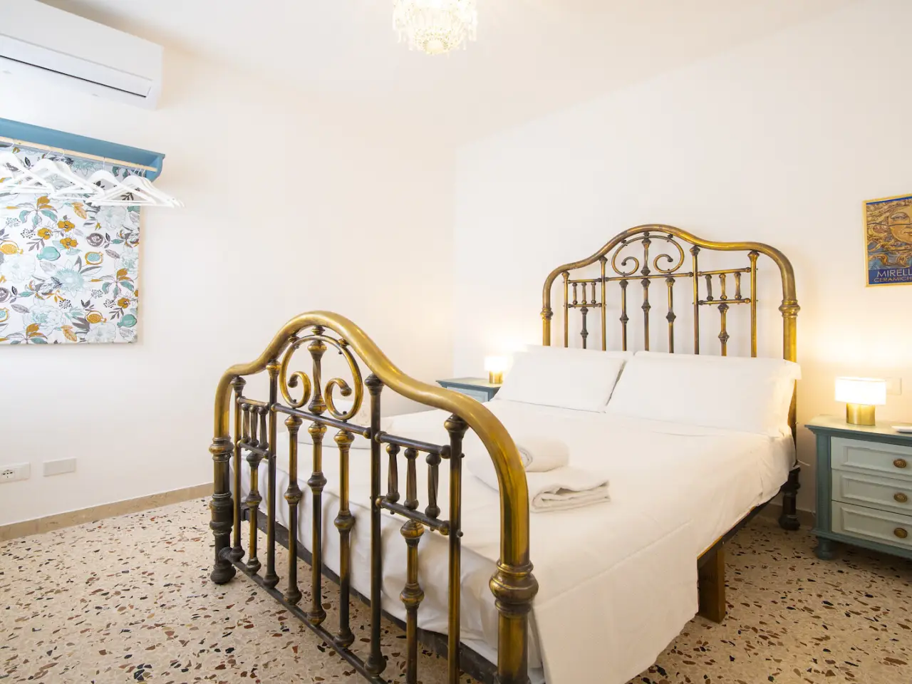 Schlafzimmer mit antikem Messingbett und türkisen Nachtkästchen