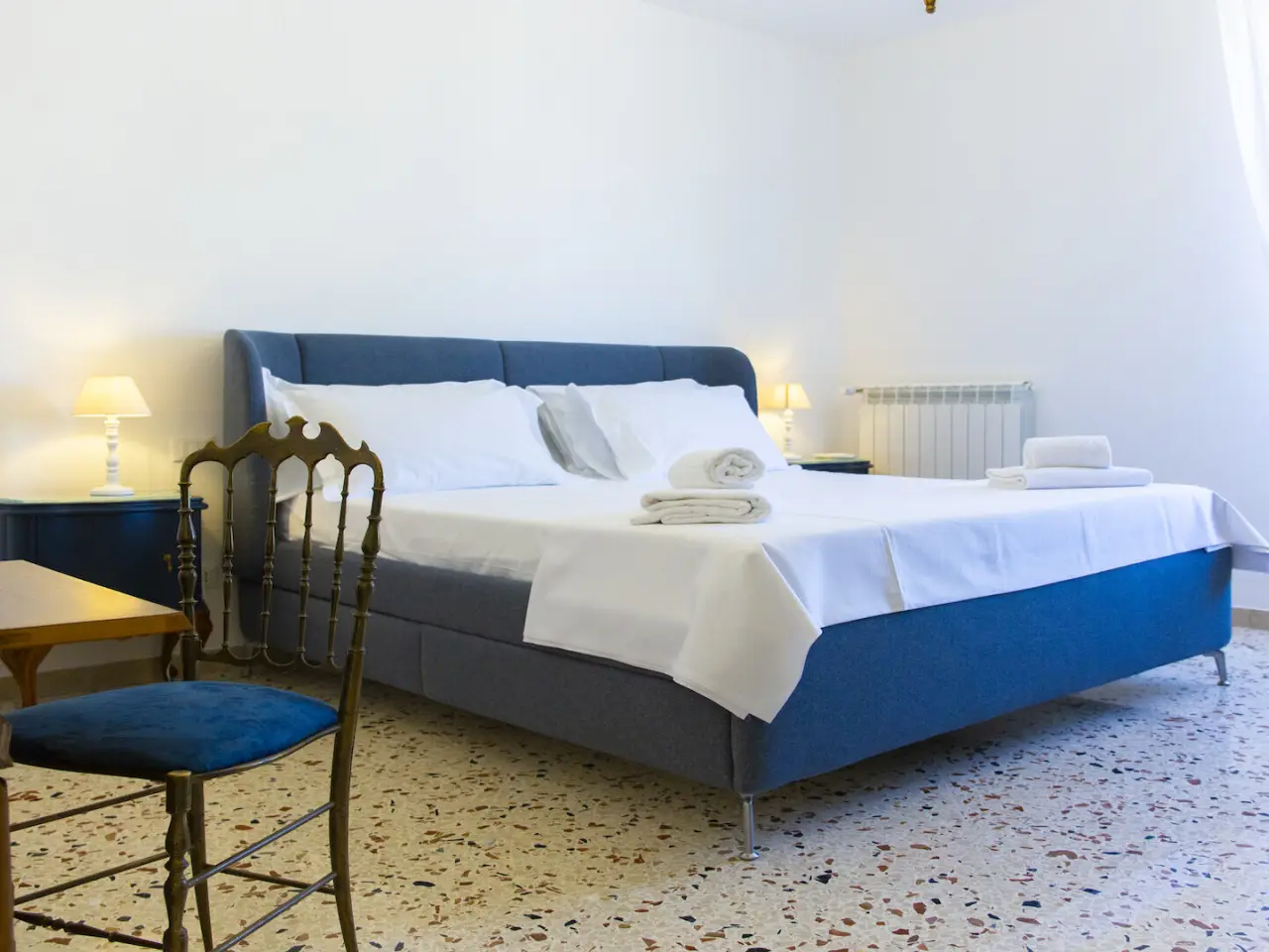 Schlafzimmer mit blauem Polsterbett und Sekretär