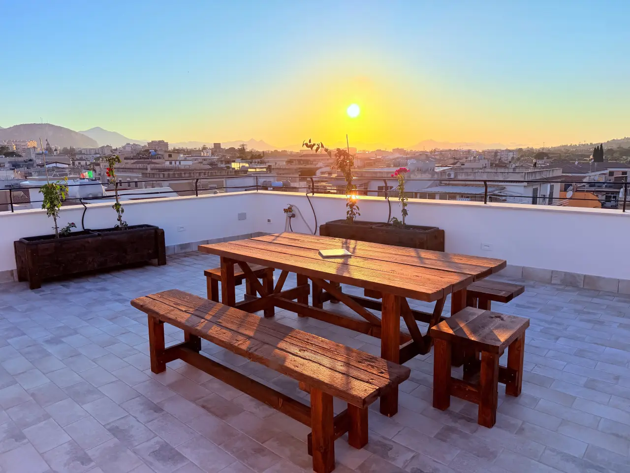 Holztisch mit Bänken auf der Dachterrasse bei Sonnenuntergang