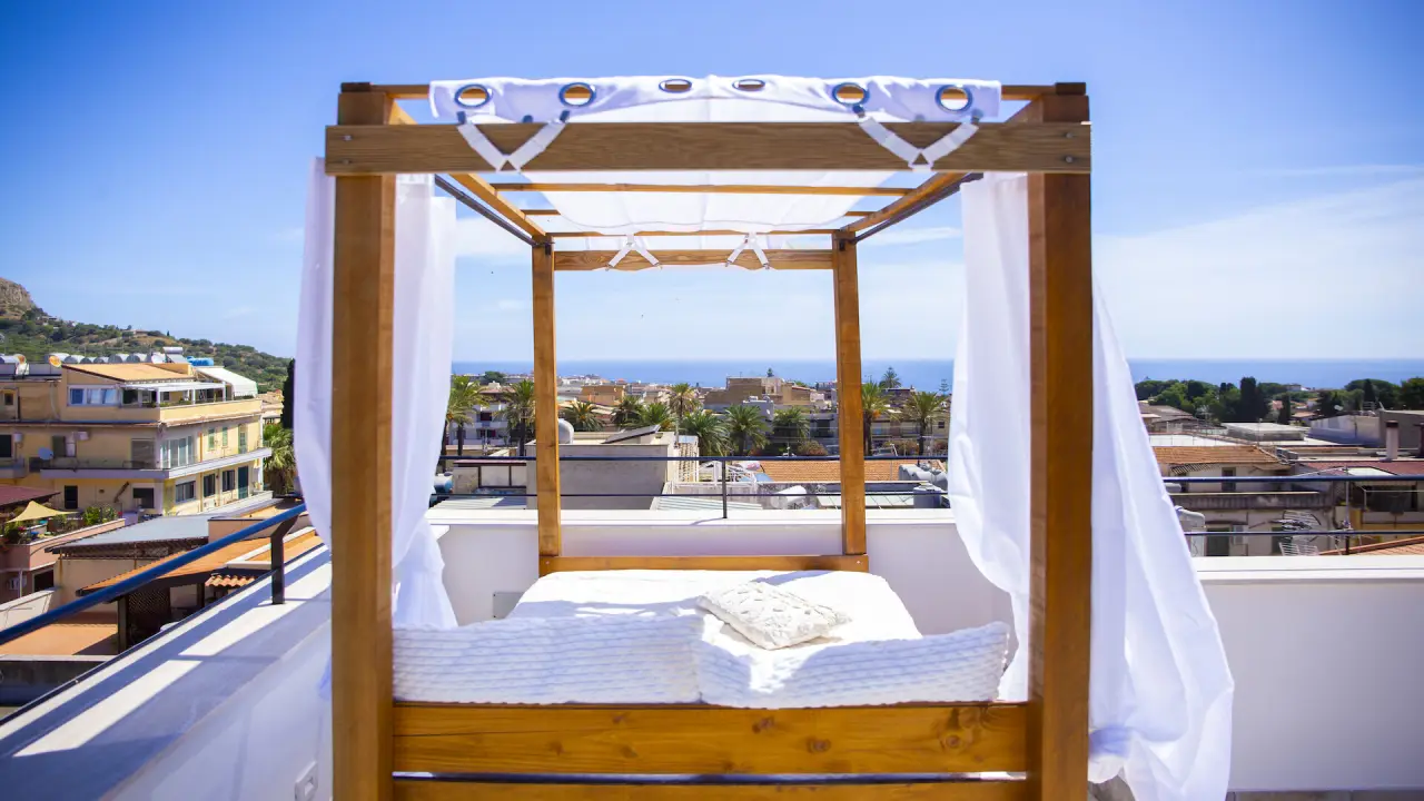 Himmelbett auf der Dachterrasse, dahinter die Dächer von Santa Flavia und das Meer