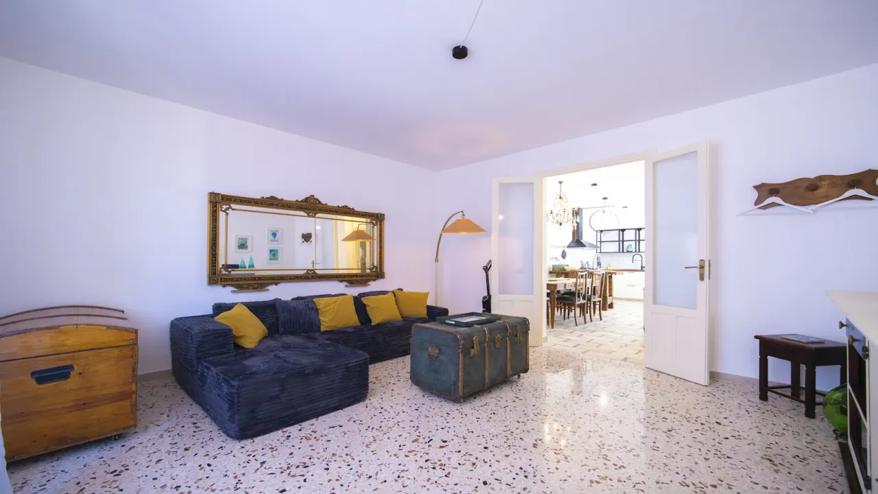 Wohnzimmer mit dunkelblauem Sofa, gelben Kissen und Terrazzoboden