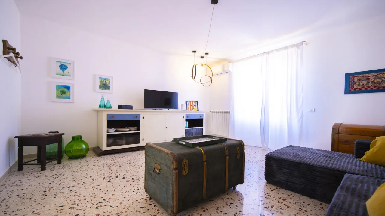 Wohnbereich mit Truhentisch, Fernseher und Keramikbildern