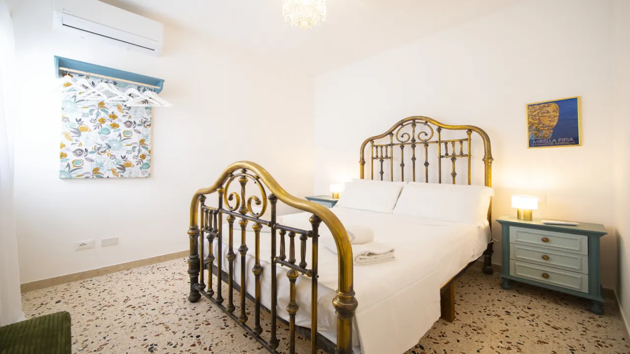 Schlafzimmer mit antikem Messingbett und türkisen Nachtkästchen