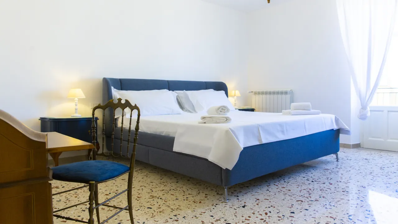 Schlafzimmer mit blauem Polsterbett und Sekretär